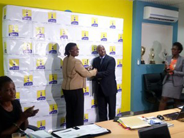 Moses Sabiiti receiving an award from URA Commissioner General, Doris Akol, on behalf of TMA