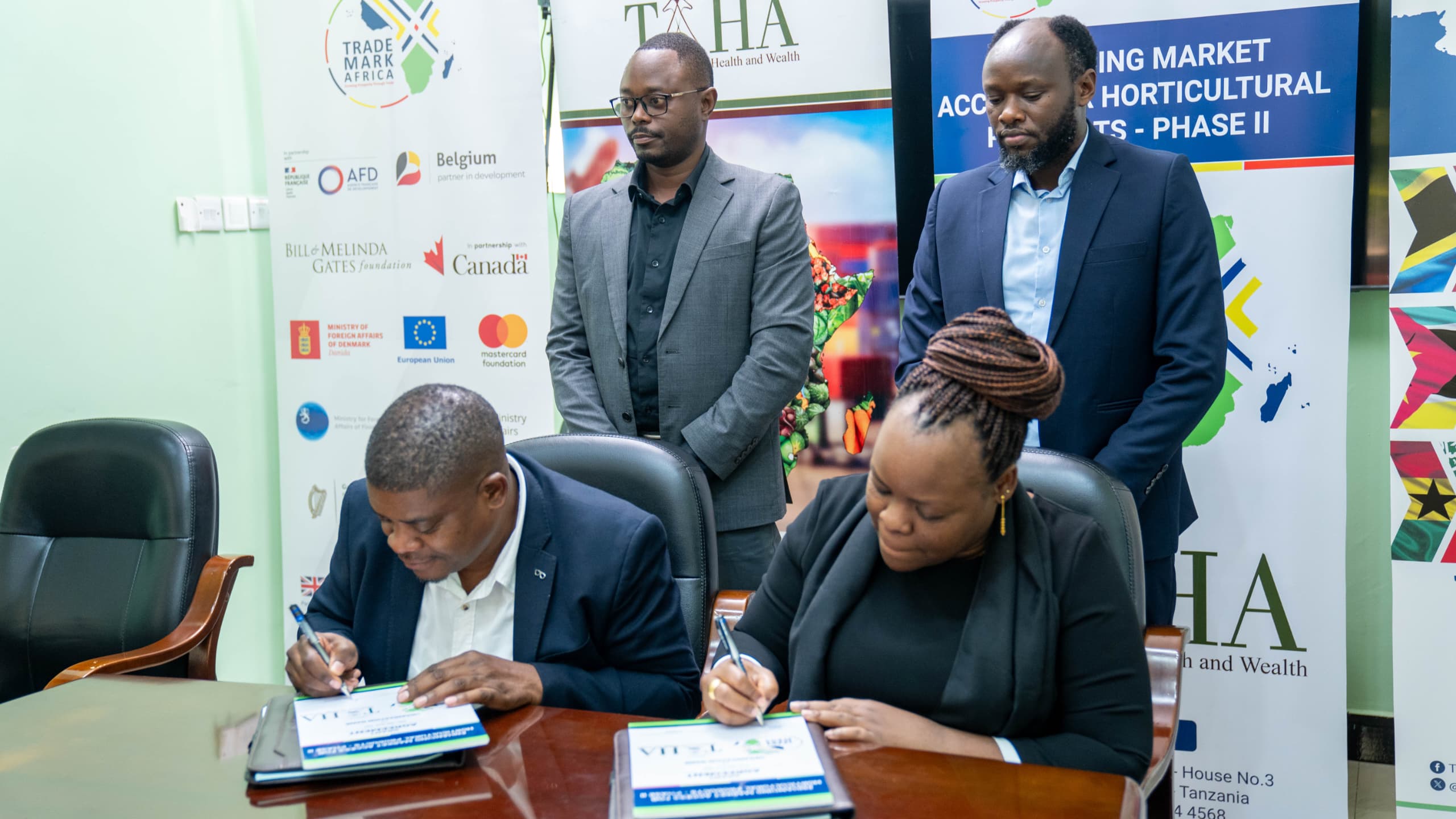 TAHA Chief Development Manager, Mr. Anthony Chamanga, and TradeMark Africa’s Regional Director for East and Central Africa, Ms. Monica Hangi signing the grant agreement. Looking on is TMA Tanzania Country Director, Elibariki Shammy (right) and Mr. Simon Mlay from TAHA